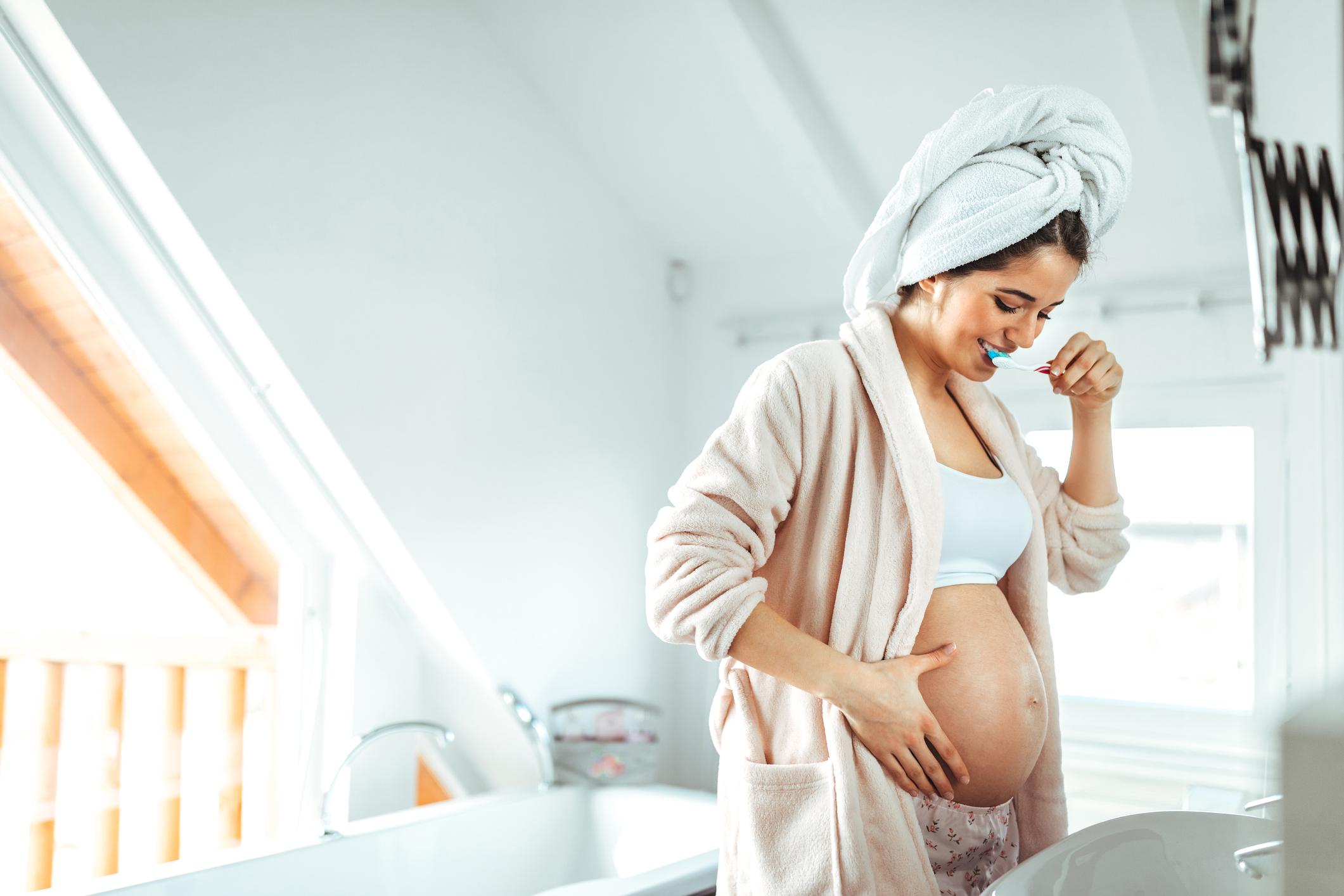 Mujer en estado de embarazo lavandose los dientes